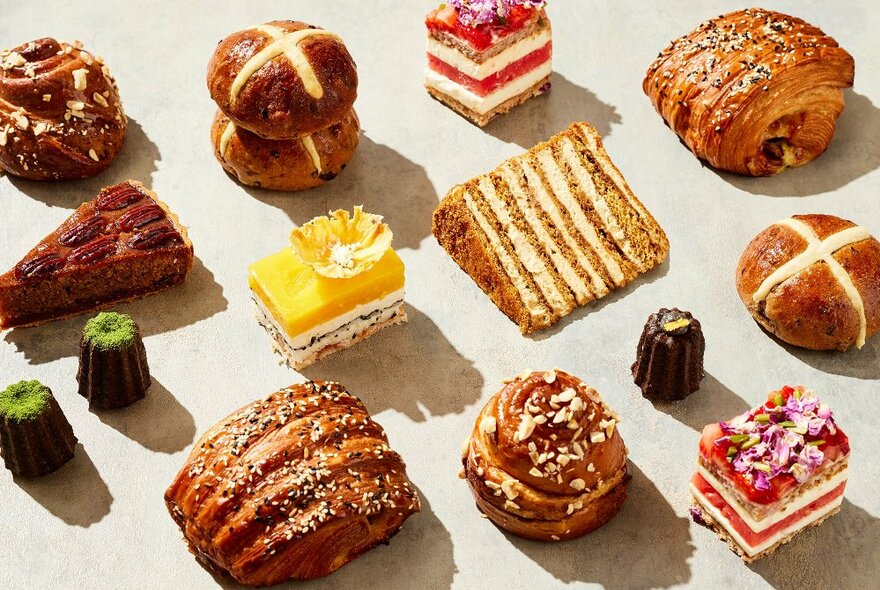 A display of baked goods including hot cross buns, cake and pastries.