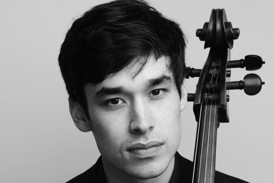 Man with dark hair holding a cello.