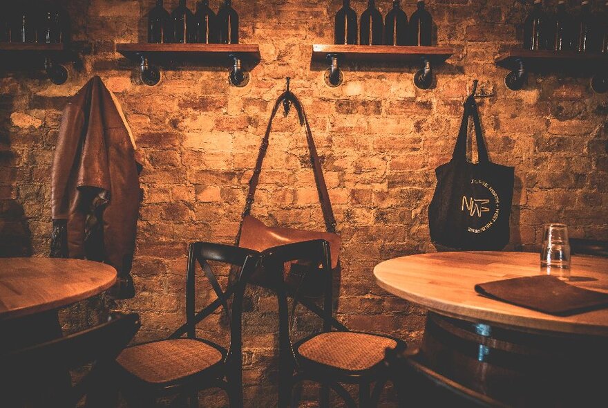 Cafe interior with exposed brick wall, and small round tables and chairs chairs.