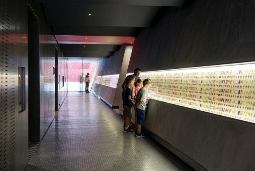 Children looking at walls of illuminated medals.