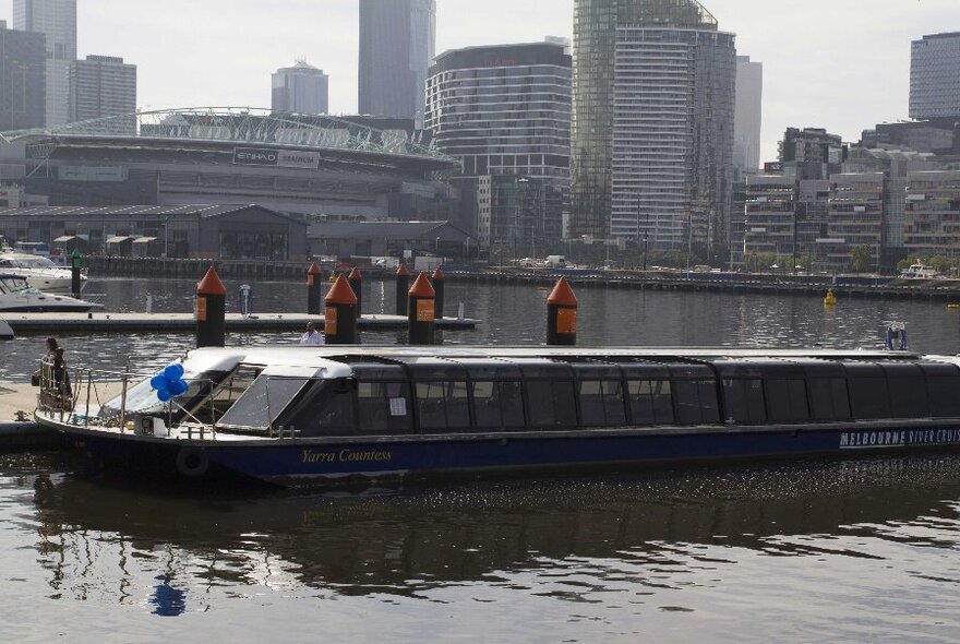 Boat in the water at Docklands with city buildings in the background.