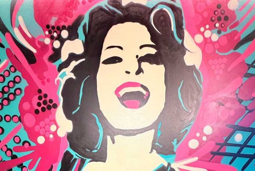 A mural of a laughing woman in tones of bright pink and blue. 