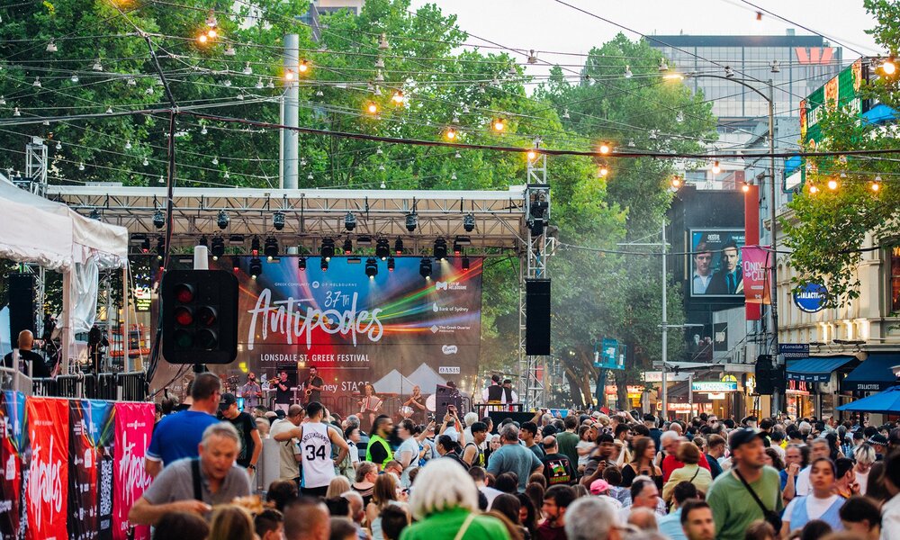A street festival in the city with crowds watching the stage.