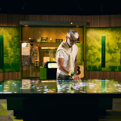 A person looking at an interactive digital tabletop in a room with green murals on the walls.