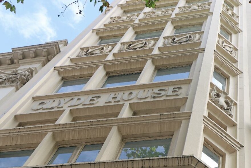 Looking up at the exterior of Hotel Collins, with 'Clyde House' on the ornate front of the building.