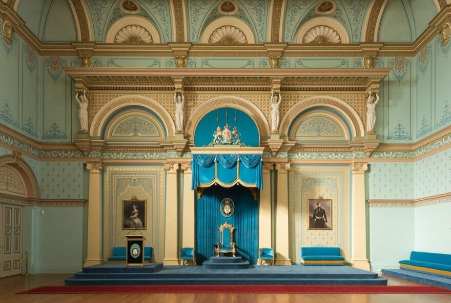 Grand reception room at Government House with pale green wallpaper, central arched dais with turquoise draped throne and seating.