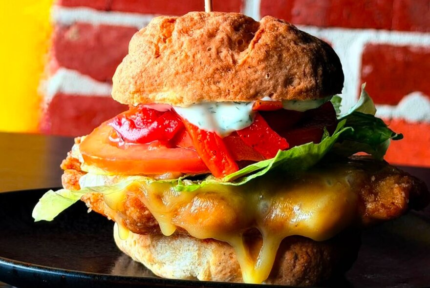 A hamburger with layers of meat, sauce and salad.