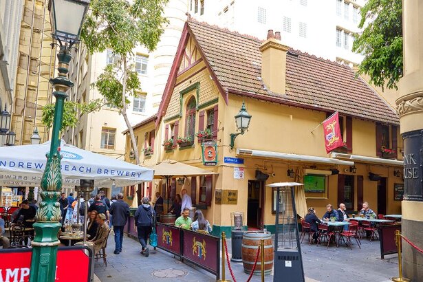 People dining in a laneway outside an old cottage-style city pub.