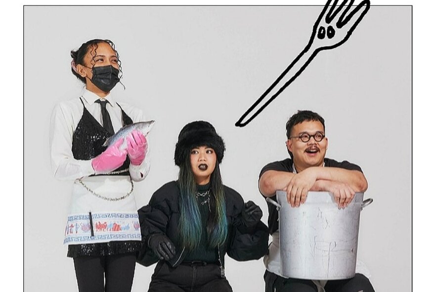 Three performers, one dressed as a waitress with pink rubber gloves and a facemask, one in all black and the other holding a large soup pot on his lap, in front of a white background overlaid with a hand-drawn fork.