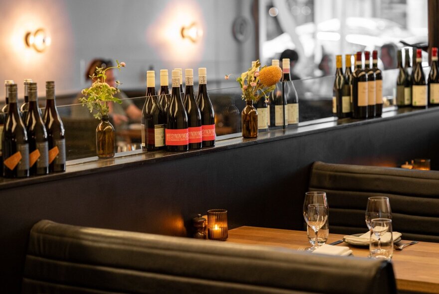 The interior of Bottega, showing a cosy booth with wine bottle displayed on a shelf against  a mirrored wall.