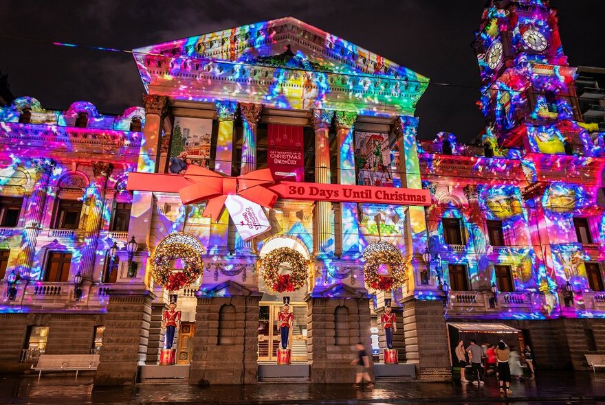 A large city building lit up with Christmas projections.