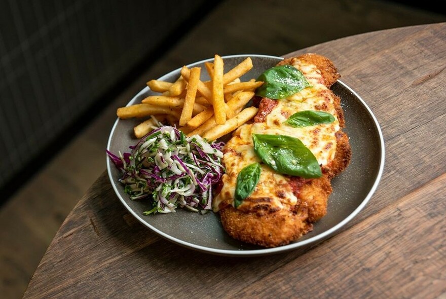 Table with dish of parmigiana and chips.