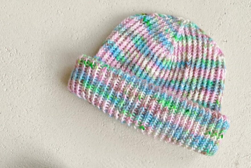 A knitted beanie in pastel striping yarn.