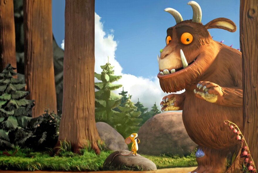 A still from the short movie, The Gruffalo, showing the Gruffalo and a little mouse standing on a rock with large tree trunks and boulders nearby.