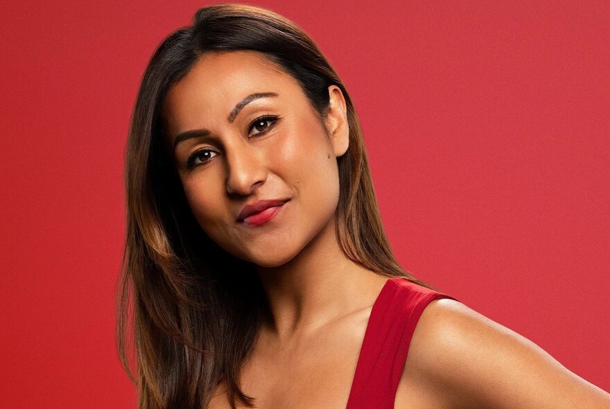 Comedian Urvi Majumdar, a young woman with long hair looking directly at viewer, wearing a red singlet top, posed against a solid red background.
