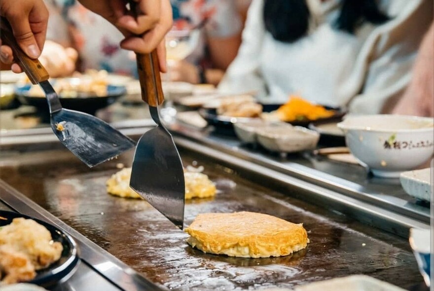 Okonomiyaki savoury Japanese pancake on a hot grill.