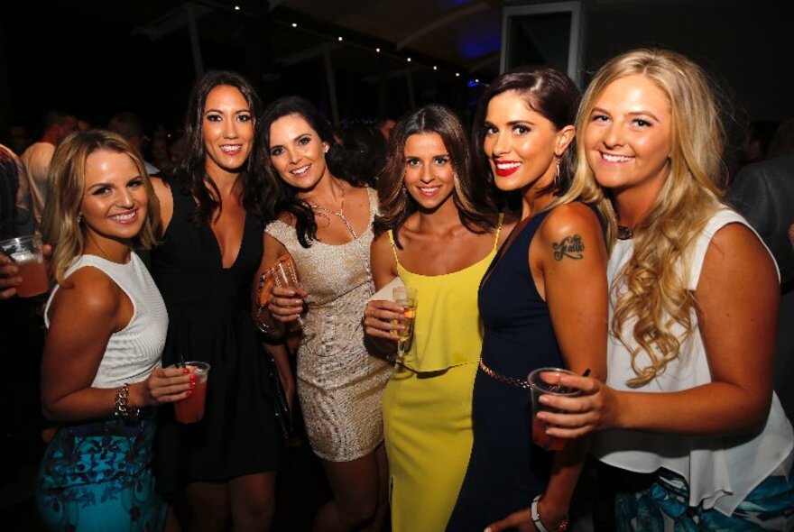 A group of beautiful women posing for a photo at a nightclub.