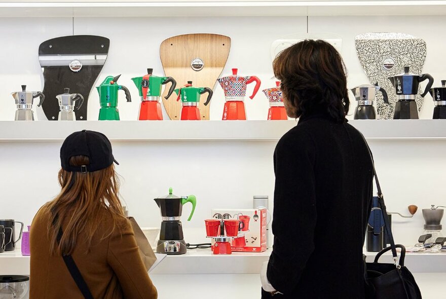 Two people looking at a store display of stovetop coffee makers.