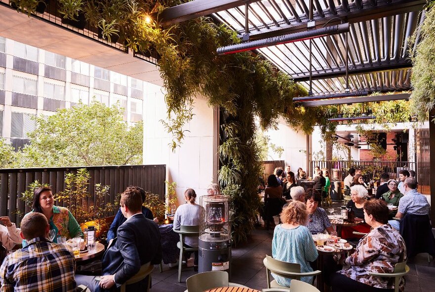 People seated in a large atrium-style outdoor rooftop section of a restaurant.