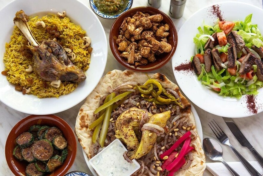 Selection of dishes including meat and rice, salad, meatballs and bread.