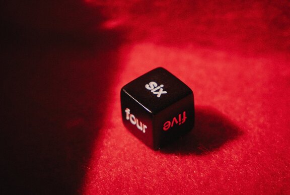 A die with numbers spelled out in letters on a red backdrop.