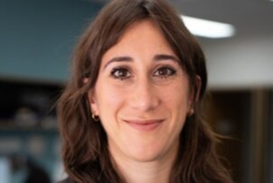 Sarah Schwartz, smiling and relaxed in a room with  a fluro light.
