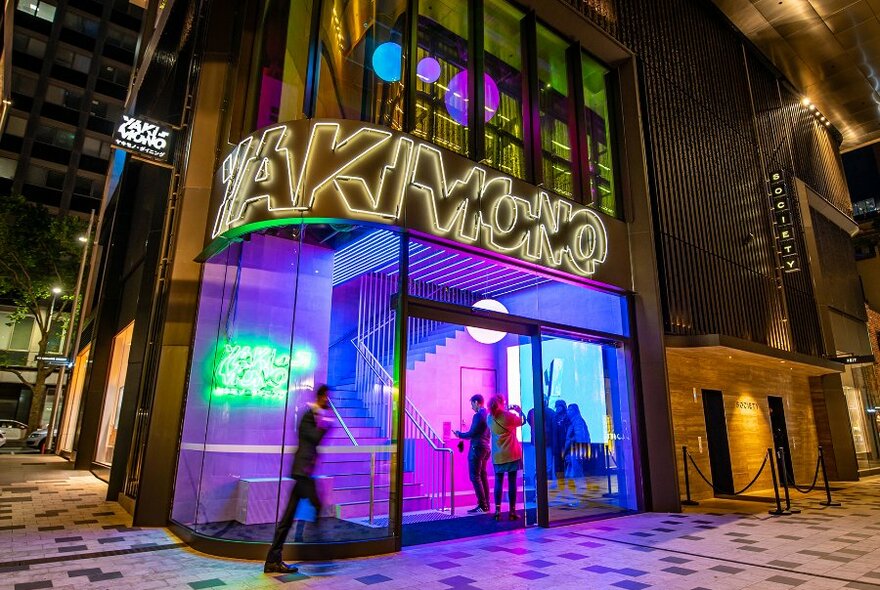 People entering a restaurant with neon lights. 