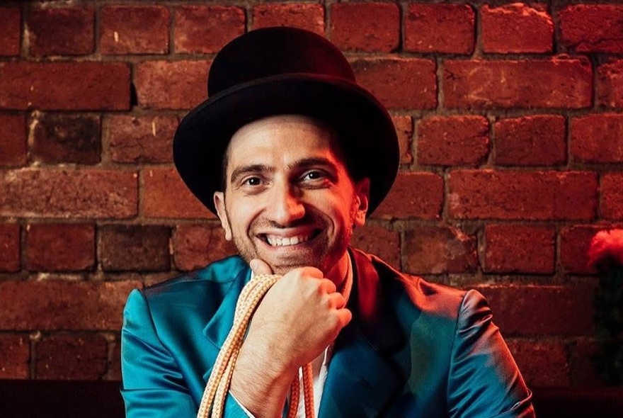 A man wearing a top hat, wearing a blue satin jacket and holding a rope.