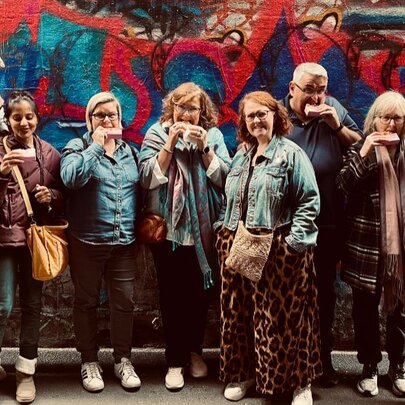 Walking group eating snacks next to a muralled wall.