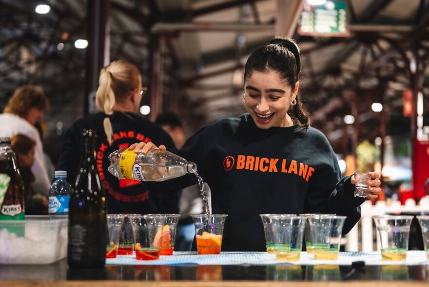 A person mixing drinks at a food and beverage stall at the Queen Victoria Night market.