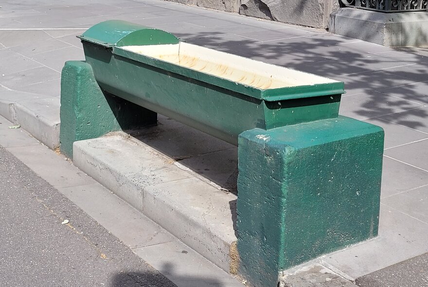 A concrete green water trough for horses to drink from, in a Melbourne city street.