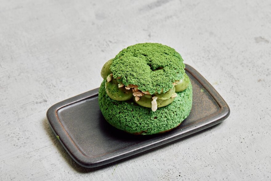 A green sweet pastry served on a small metal tray.