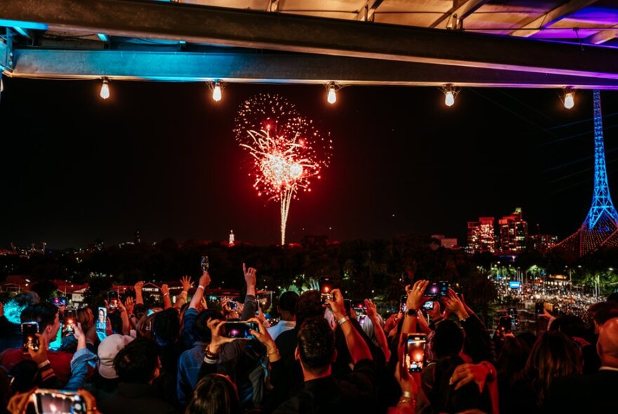 View of the New Year's Eve fireworks from the terrace of Transit Rooftop Bar, with people standing on the balcony.