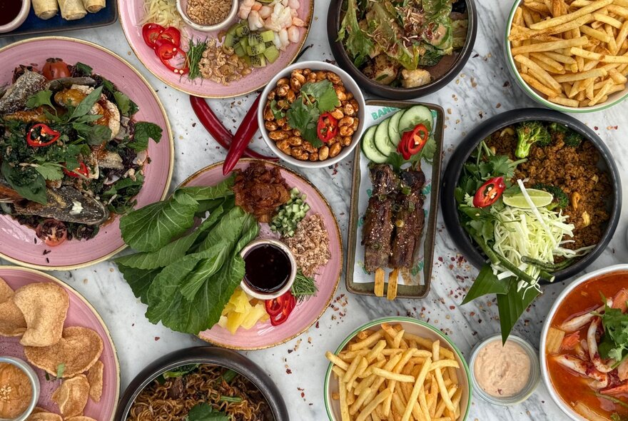 Looking down on a table heaving wtih many plates at a Thai banquet. 
