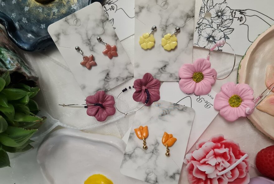 Pairs of floral-shaped clay earrings pinned to cards, including petalled flowers and tulips.