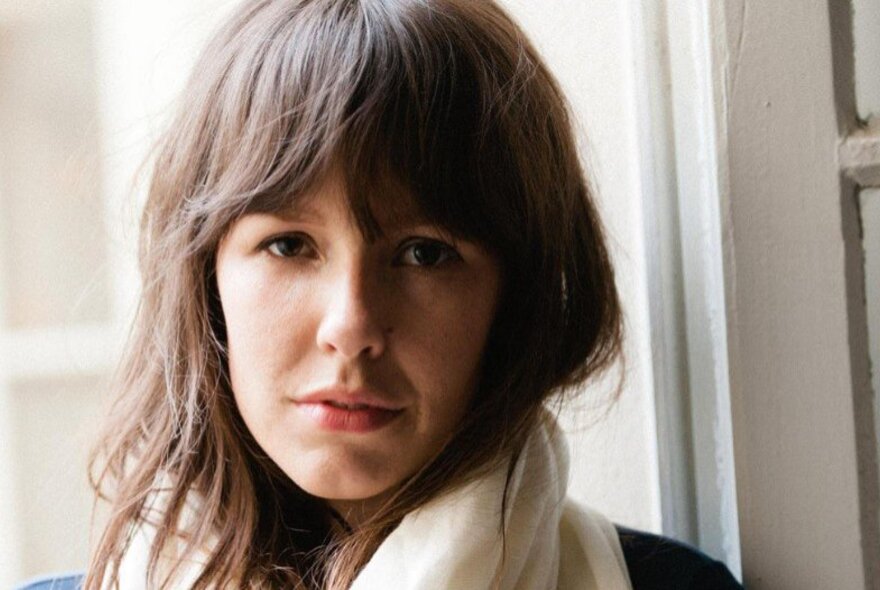 A head shot of author Tara June Winch, a white scarf around her neck. 