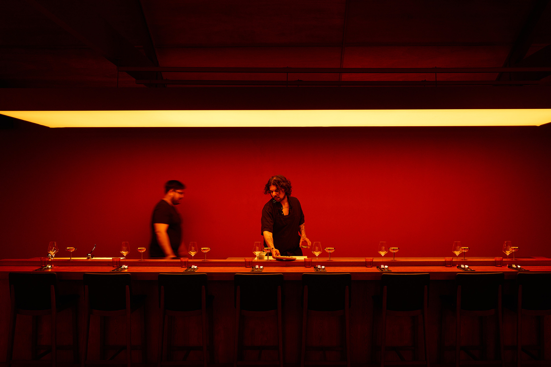 Two people are working at a dimly lit sushi bar