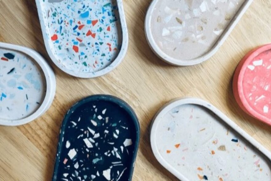 Six oval shaped terrazzo trinket trays made from resin in different colours.