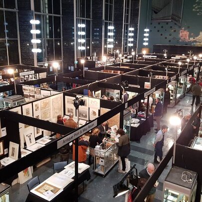 Overhead view of temporary book stalls filling Wilson Hall with people walking around looking at the products for sale.