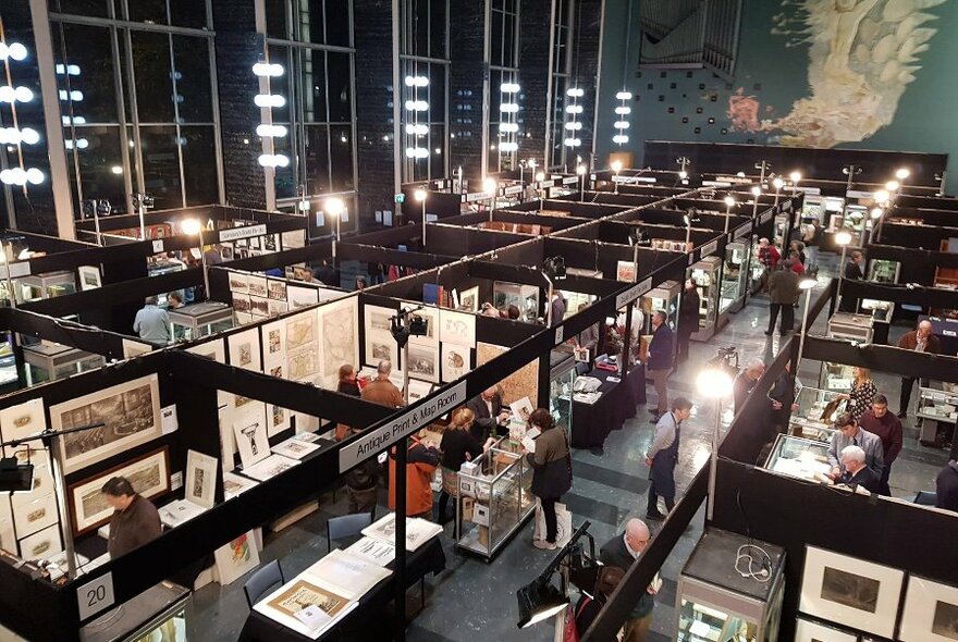 Overhead view of temporary book stalls filling Wilson Hall with people walking around looking at the products for sale.