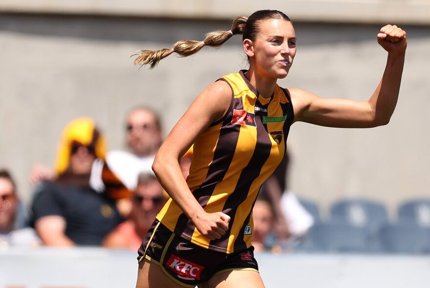 AFLW Hawthorn football player running with arm clenched in the air.