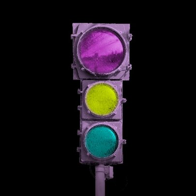 A purple traffic light with pink, yellow, and teal lights against a black background.