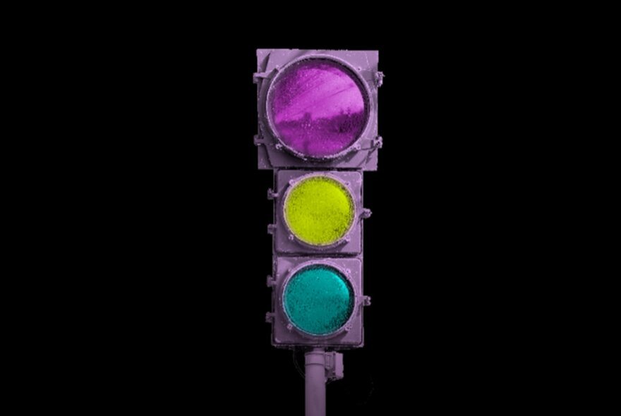 A purple traffic light with pink, yellow, and teal lights against a black background.