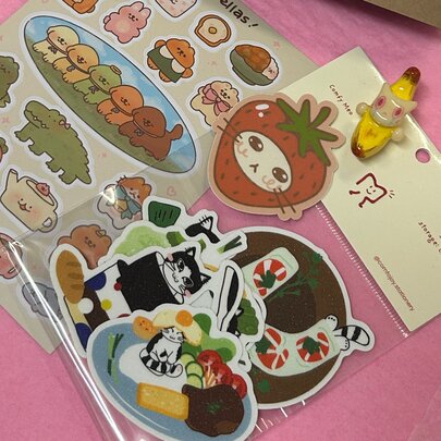 Looking on casually arranged sheets of cat stickers on a pink surface. 