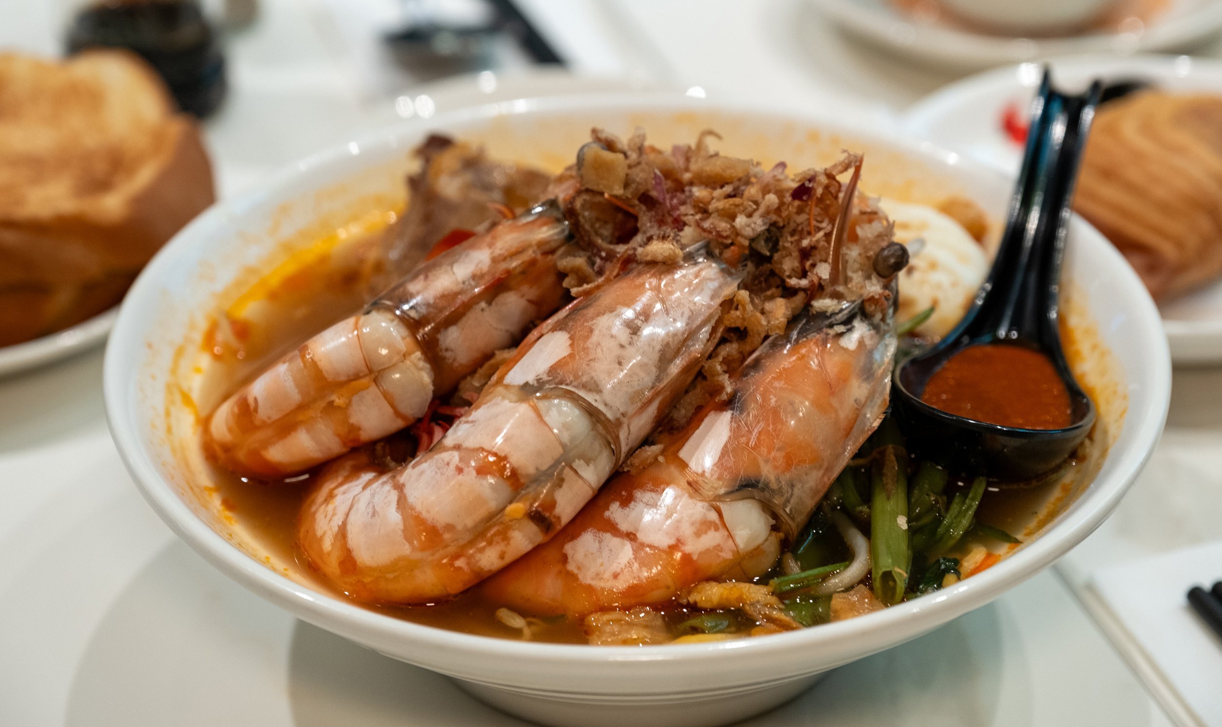 A bowl of laksa with giant prawns in it.