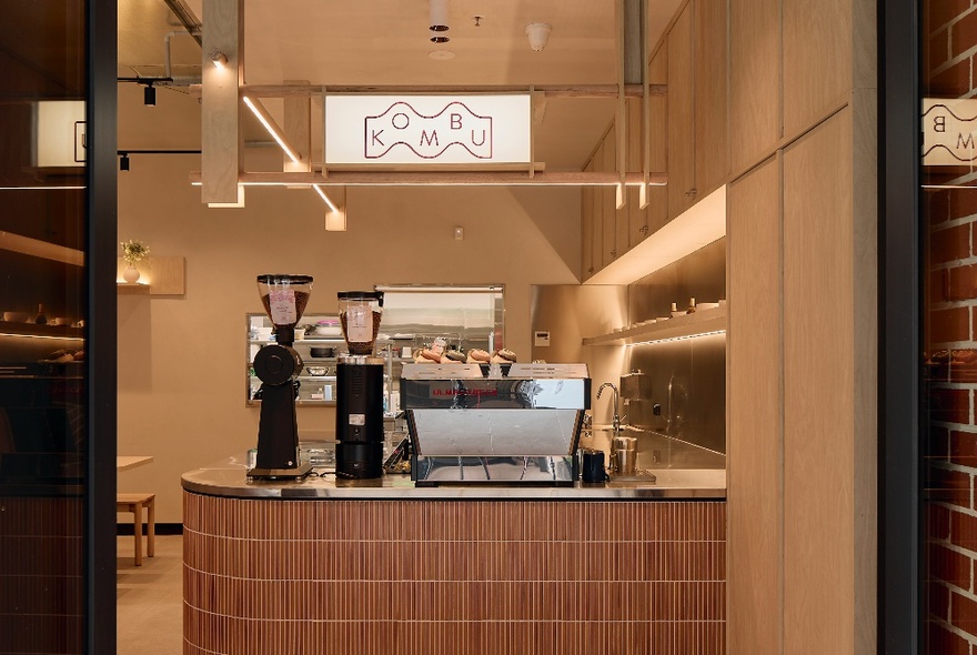 The cosy interior of Kombu Japanese cafe at QVM, showing a counter area with a coffee machine.