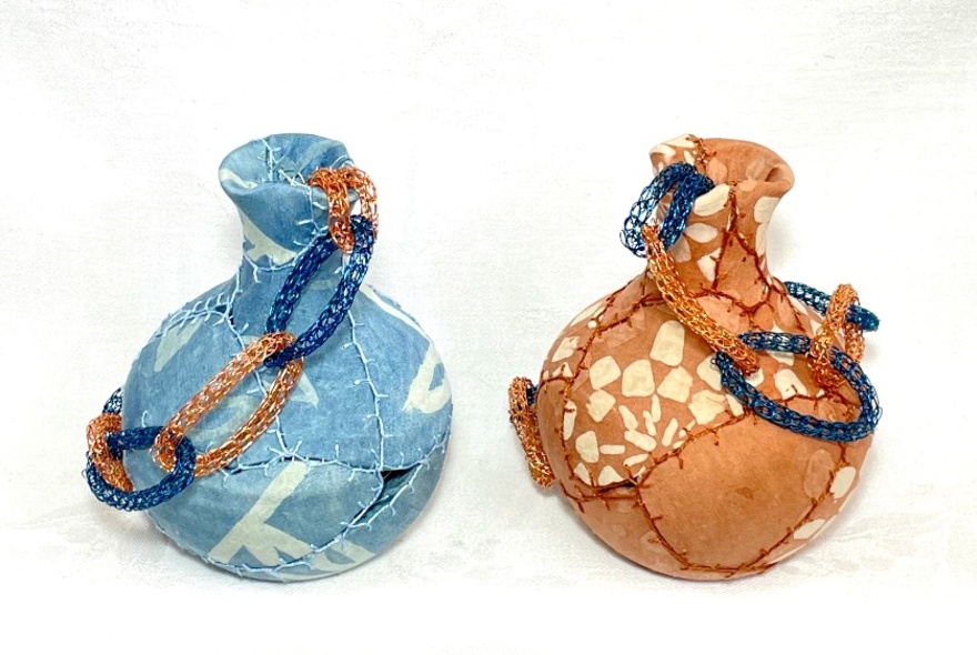 Two small hand-crafted vessels of blue and tan, made from textiles.