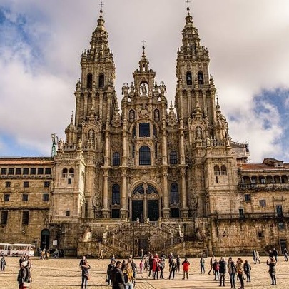 Cathedral of Santiago de Compostela in Galicia, Spain - an imposing structure with a large piazza in the foreground and many people walking around.