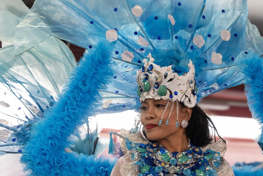 An Indonesian dancer dressed in an elaborate blue feathered headress and costume.