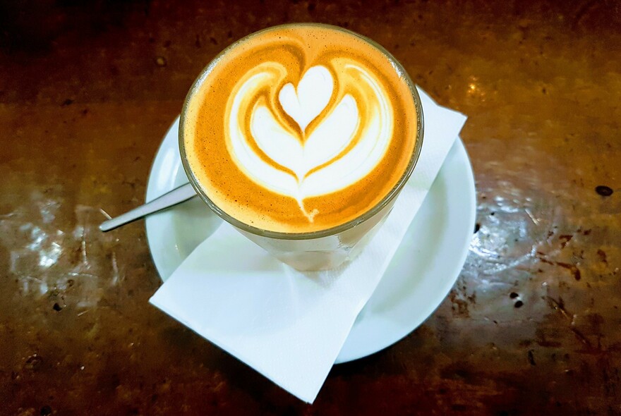 A caffe latte with abstract heart design, on a wooden table.